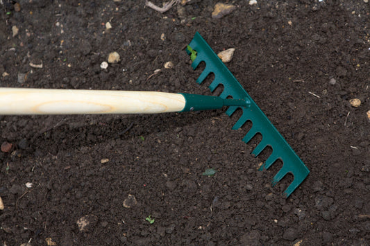 Garden rake smoothing soil in preparation for planting