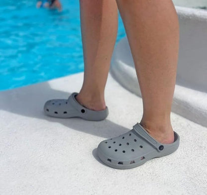 Person wearing gray clogs by a pool