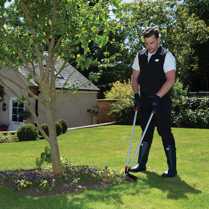 Man gardening using a Wilkinson Sword long reach edging shears for creating neat lawn borders and pathways in a well-maintained lawn with a tree and house in the background