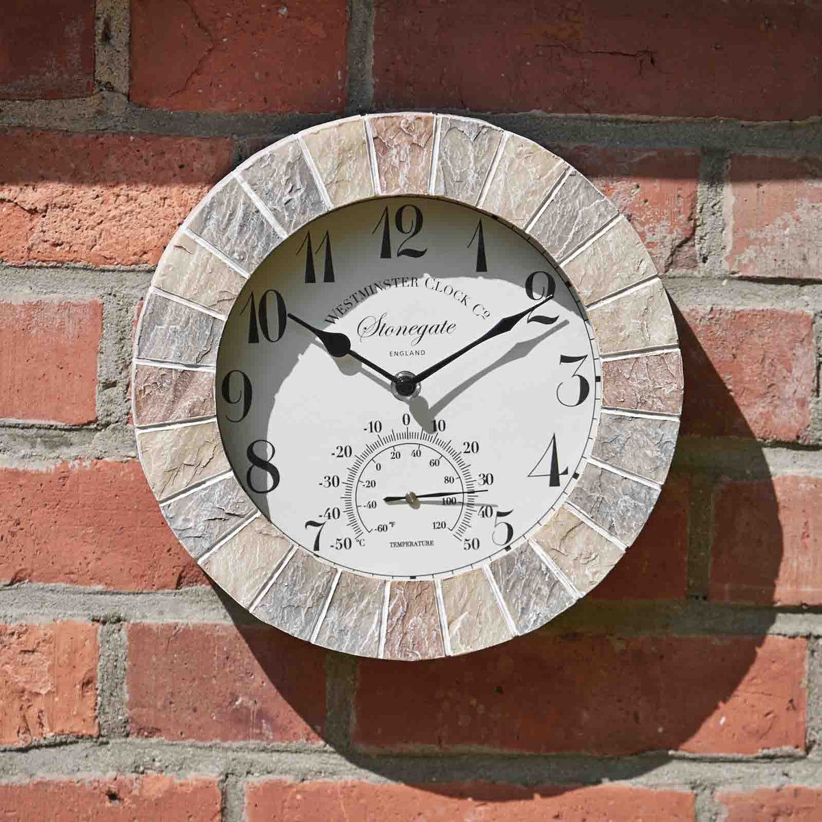 Round outdoor clock with stone-like design on a brick wall