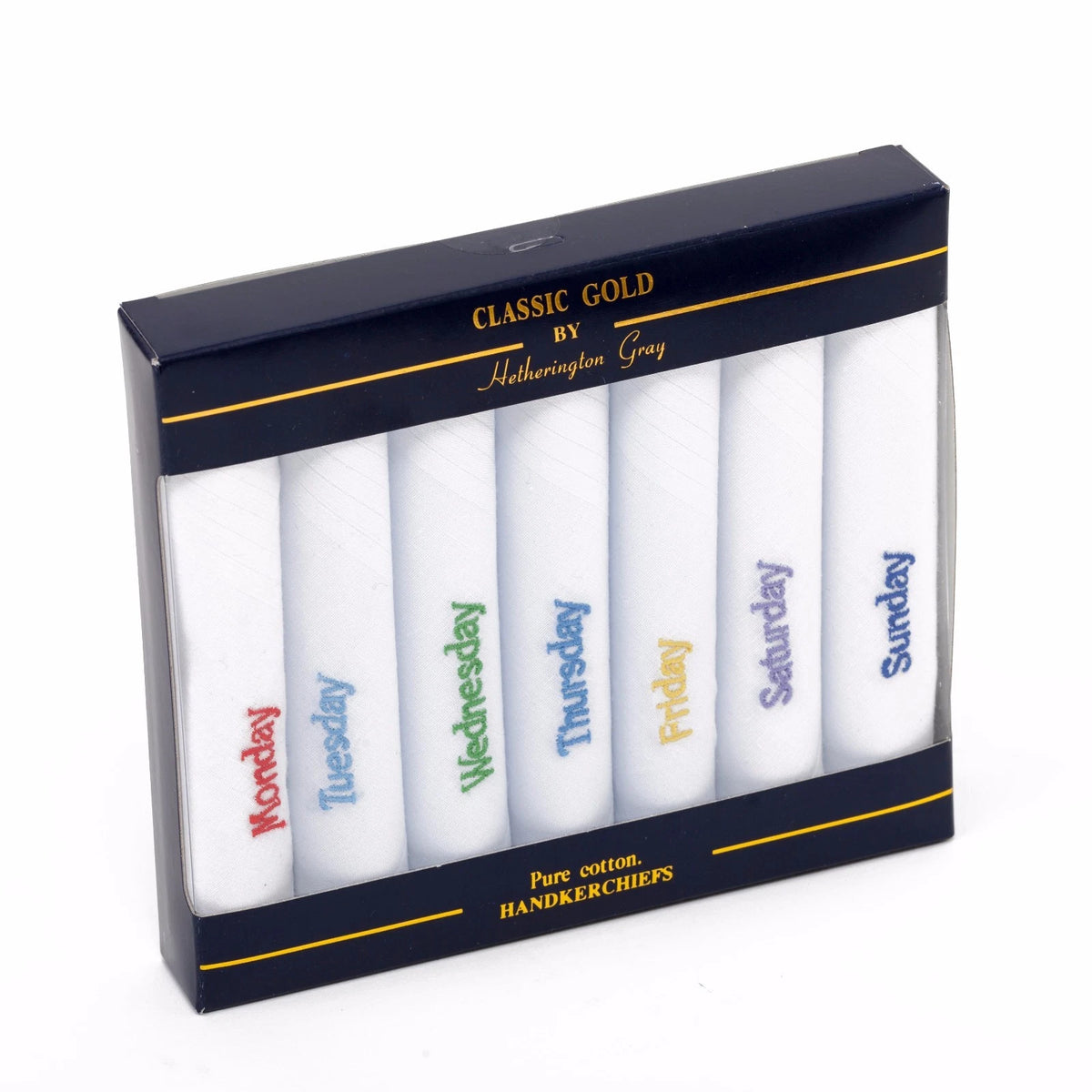 A boxed set of six white cotton handkerchiefs in a dark navy retail package. The handkerchiefs are labeled with the days of the week in different colors: Monday red, Tuesday blue, Wednesday green, Thursday dark blue, Friday yellow, Saturday purple.