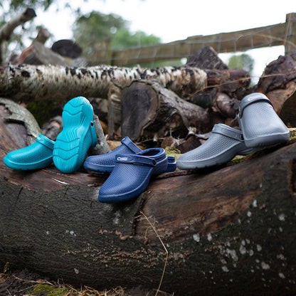 Three pairs of shoes in blue, green, and gray on a log with a natural background.
