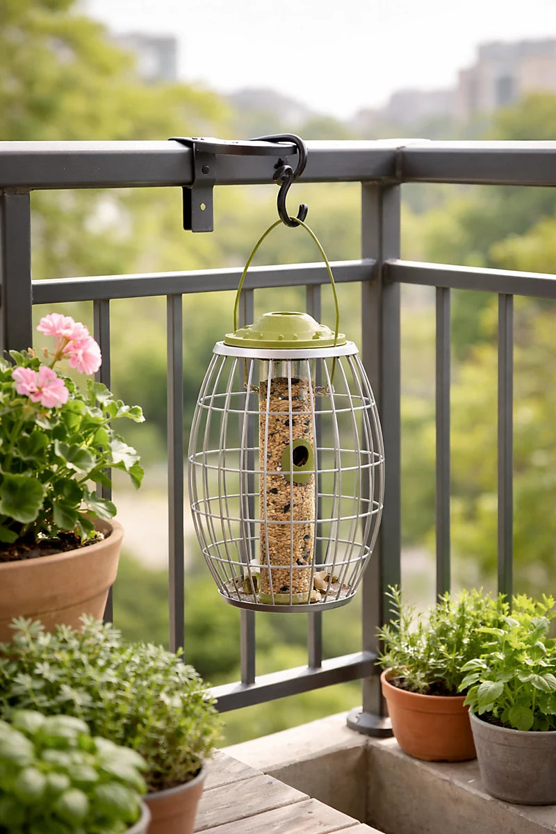 Bird feeder hanging on a balcony railing with plants and flowers below