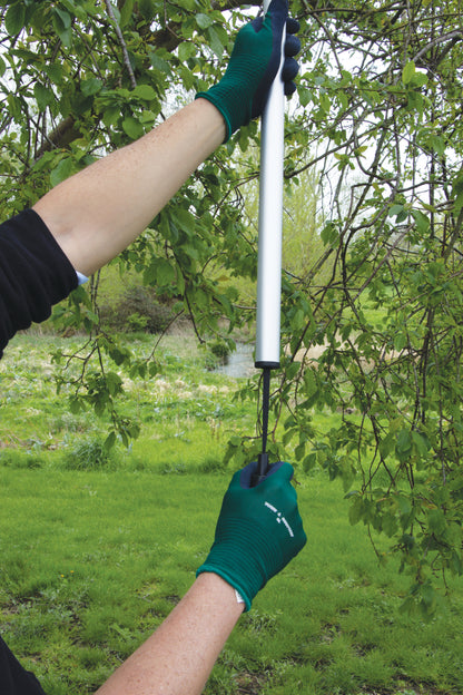 Person using a long-handled tool to trim branches in a garden